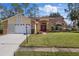 Well-maintained home with stone accents, a red front door, and a lush green lawn at 9652 Oakwood Hills Ct, New Port Richey, FL 34655