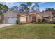 Inviting single-Gathering home featuring stone accents, a manicured lawn, and a two-car garage at 9652 Oakwood Hills Ct, New Port Richey, FL 34655