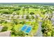 A lush, green aerial view of tennis courts, a pond, beautiful homes, and mature trees at 11041 Paradise Point Way, New Port Richey, FL 34654