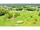 Panoramic aerial view featuring golf course, pond, and mature trees against a wooded backdrop, showcasing the community at 11041 Paradise Point Way, New Port Richey, FL 34654