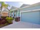 A charming light-blue home featuring a two-car garage, decorative pillars, and lush landscaping at 11041 Paradise Point Way, New Port Richey, FL 34654
