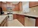 Well-lit kitchen featuring stainless steel appliances, tile flooring, granite countertops, and wood cabinetry at 11041 Paradise Point Way, New Port Richey, FL 34654