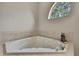 Corner bathtub with tile surround and half round window overlooking the greenery outside at 11336 Flower Ave, Weeki Wachee, FL 34613