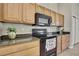 Close-up of black range and microwave with wood cabinets and granite countertops in the kitchen at 11336 Flower Ave, Weeki Wachee, FL 34613