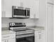 Close-up of a modern kitchen's stainless steel oven, microwave, and white cabinets at 12331 Fulmar Rd, Weeki Wachee, FL 34614