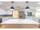 Bright kitchen features white cabinets, stainless steel appliances, island with quartz countertop, and stylish pendant lighting at 12709 Castleberry Ct, Hudson, FL 34667