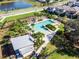 Aerial view of a community pool area with palm trees, lounge chairs, and a nearby lake and residential houses at 12889 Burns Dr, Odessa, FL 33556