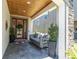 Inviting front porch with stone detail, brick flooring, a wooden ceiling, and a porch swing at 12889 Burns Dr, Odessa, FL 33556