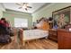 Bedroom with wood floor, ceiling fan, unmade bed, and assorted clutter at 13810 Celida Ave, Hudson, FL 34667