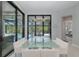 Contemporary dining room with glass table, white chairs, modern chandelier, and views of the screened pool area at 16557 Acoustic Loop, Land O Lakes, FL 34638