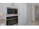 Built-in stainless steel microwave and oven with white cabinets and access to a large pantry at 16557 Acoustic Loop, Land O Lakes, FL 34638