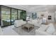 Bright living room with white sofas, a modern rug, and a view of the screened pool area through sliding glass doors at 16557 Acoustic Loop, Land O Lakes, FL 34638
