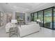 Open living area with white tile floors, comfortable seating, and sliding doors leading to the outdoor pool area at 16557 Acoustic Loop, Land O Lakes, FL 34638