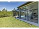 Screened-in pool and patio with modern seating, an outdoor kitchen, and lush green lawn at 16557 Acoustic Loop, Land O Lakes, FL 34638