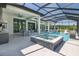 A luxurious screened-in pool and hot tub surrounded by outdoor cooking, dining, and lounging areas at 16557 Acoustic Loop, Land O Lakes, FL 34638