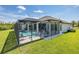 Wide angle showcasing the screened-in pool, patio, and manicured lawn of the home's exterior at 16557 Acoustic Loop, Land O Lakes, FL 34638