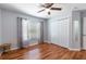 Bright bedroom featuring wood floors, ceiling fan, window with curtains, and a closet at 18353 Briar Oaks Dr, Hudson, FL 34667