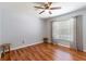 Sunlit bedroom featuring wood floors, a ceiling fan, and a window with curtains at 18353 Briar Oaks Dr, Hudson, FL 34667