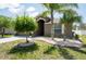 Well-maintained front yard showcasing lush landscaping, mature trees, and stone accents enhance the home's exterior at 18353 Briar Oaks Dr, Hudson, FL 34667