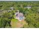 Stunning aerial view of a home surrounded by lush trees, featuring a screened pool, solar panels, and an expansive yard at 18502 Winding Oaks Blvd, Hudson, FL 34667