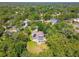 Aerial view of a home with a pool, solar panels, and brick driveway in a lush, maturely wooded community at 18502 Winding Oaks Blvd, Hudson, FL 34667