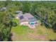 Aerial view of a home with a screened-in pool, solar panels, and a large, well-kept yard surrounded by trees at 18502 Winding Oaks Blvd, Hudson, FL 34667