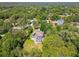 Aerial view of a community with a pool surrounded by mature trees adding privacy with a brick driveway at 18502 Winding Oaks Blvd, Hudson, FL 34667