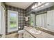 Neutral-toned bathroom features a white vanity, framed mirror, gold hardware and a patterned wallpaper at 18502 Winding Oaks Blvd, Hudson, FL 34667