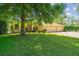 Lovely yellow single-story home with well-kept lawn, neat shrubbery, and three car garage at 18502 Winding Oaks Blvd, Hudson, FL 34667