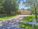 Charming front exterior with a brick driveway, three-car garage, and mature trees at 18502 Winding Oaks Blvd, Hudson, FL 34667
