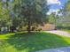 Inviting single-story home featuring a lush lawn, mature tree and a brick paver driveway leading to a three-car garage at 18502 Winding Oaks Blvd, Hudson, FL 34667