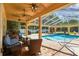 Covered patio with comfortable seating, ceiling fans, and view of the pool and backyard at 18502 Winding Oaks Blvd, Hudson, FL 34667