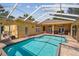 Enclosed pool area with sunny brick patio, ample seating, and multiple access points to the home at 18502 Winding Oaks Blvd, Hudson, FL 34667