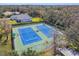 Aerial view of two well-maintained blue and green tennis courts with a house in the background at 18502 Winding Oaks Blvd, Hudson, FL 34667