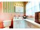Colorful bathroom with pink tile, striped wallpaper and white vanity sink at 1919 Harpoon Dr, Holiday, FL 34690