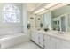 Bright bathroom featuring a double sink vanity, garden tub, decorative window, and a separate glass-enclosed shower at 2327 Morning Glory Trl, Spring Hill, FL 34606