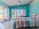 Bedroom with sliding glass doors that lead outside, colorful bedspread, turquoise walls, and lots of natural light at 2327 Morning Glory Trl, Spring Hill, FL 34606