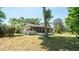 Home's back exterior showing a covered and screened porch, surrounded by trees and a chain link fence at 23409 Dogwood Estates Dr, Brooksville, FL 34601