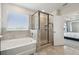Bathroom featuring tiled shower and tub, enhanced by natural light and direct access to the main bedroom at 3208 Living Coral Dr, Odessa, FL 33556