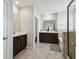 Bathroom featuring double vanities, dark cabinets, and tile flooring, complemented by natural light at 3208 Living Coral Dr, Odessa, FL 33556