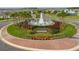 Aerial view of community entrance featuring a decorative fountain, landscaping, and roundabout at 3208 Living Coral Dr, Odessa, FL 33556