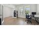 Bright home office with wood-look tile flooring, large windows, and a modern desk setup at 3208 Living Coral Dr, Odessa, FL 33556
