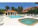 Community pool with lounge chairs, lush landscaping, and a charming clubhouse in a tropical setting at 3655 Square West Ln # 9, Sarasota, FL 34238