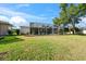 Lush green backyard featuring a screened-in pool area, mature trees, and manicured lawn at 4080 Gevalia Dr, Brooksville, FL 34604