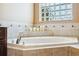 Bathroom featuring soaking tub with tile surround and a glass block window at 4080 Gevalia Dr, Brooksville, FL 34604