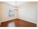 A view of the dining room with wood floors, a chandelier, an arched window, and neutral colored walls at 4080 Gevalia Dr, Brooksville, FL 34604