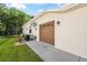 Beige home featuring a brown garage door, air conditioning unit, lush lawn, and a sunny blue sky at 4080 Gevalia Dr, Brooksville, FL 34604