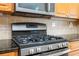 Close-up of a black gas range and stainless microwave with wooden cabinets and backsplash at 4080 Gevalia Dr, Brooksville, FL 34604