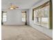 Bright living room featuring neutral carpet, ceiling fan and large windows dressed with attractive green drapes at 4335 Duval St, Spring Hill, FL 34606