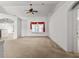 Spacious living room with neutral walls, carpeted floors, and a large window with red curtains at 4335 Duval St, Spring Hill, FL 34606